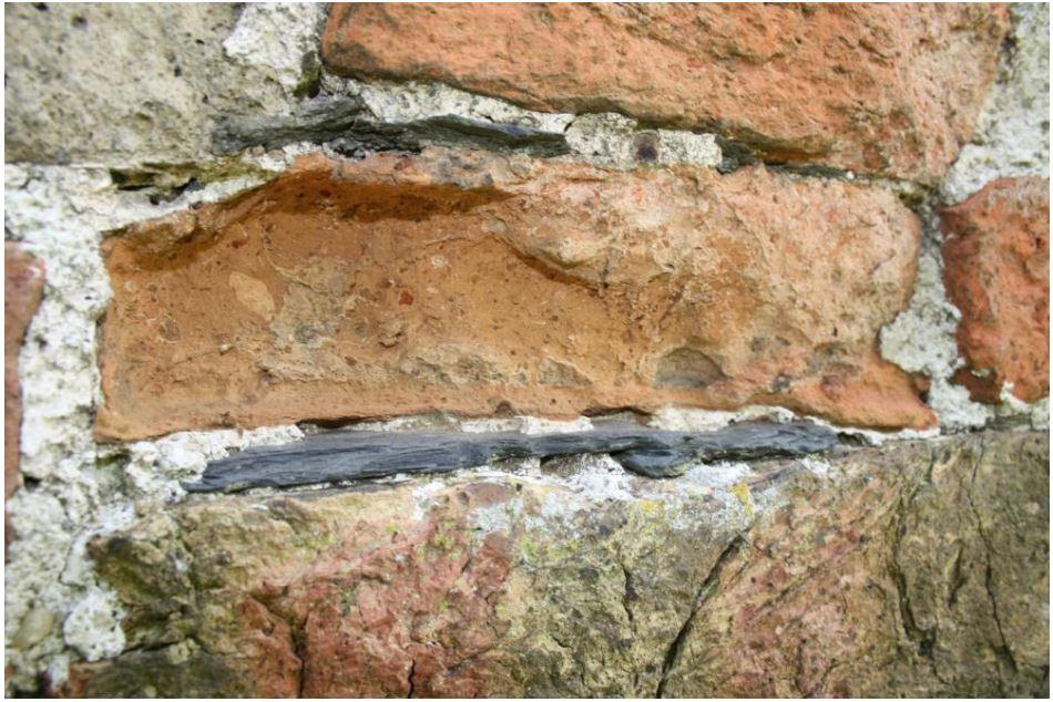 Leisteenfragmenten ingebed in de mortel tussen de voegen van muren (kerktoren van Zuidwolde, NL) (Foto uit Van Ens, 2019, 34)